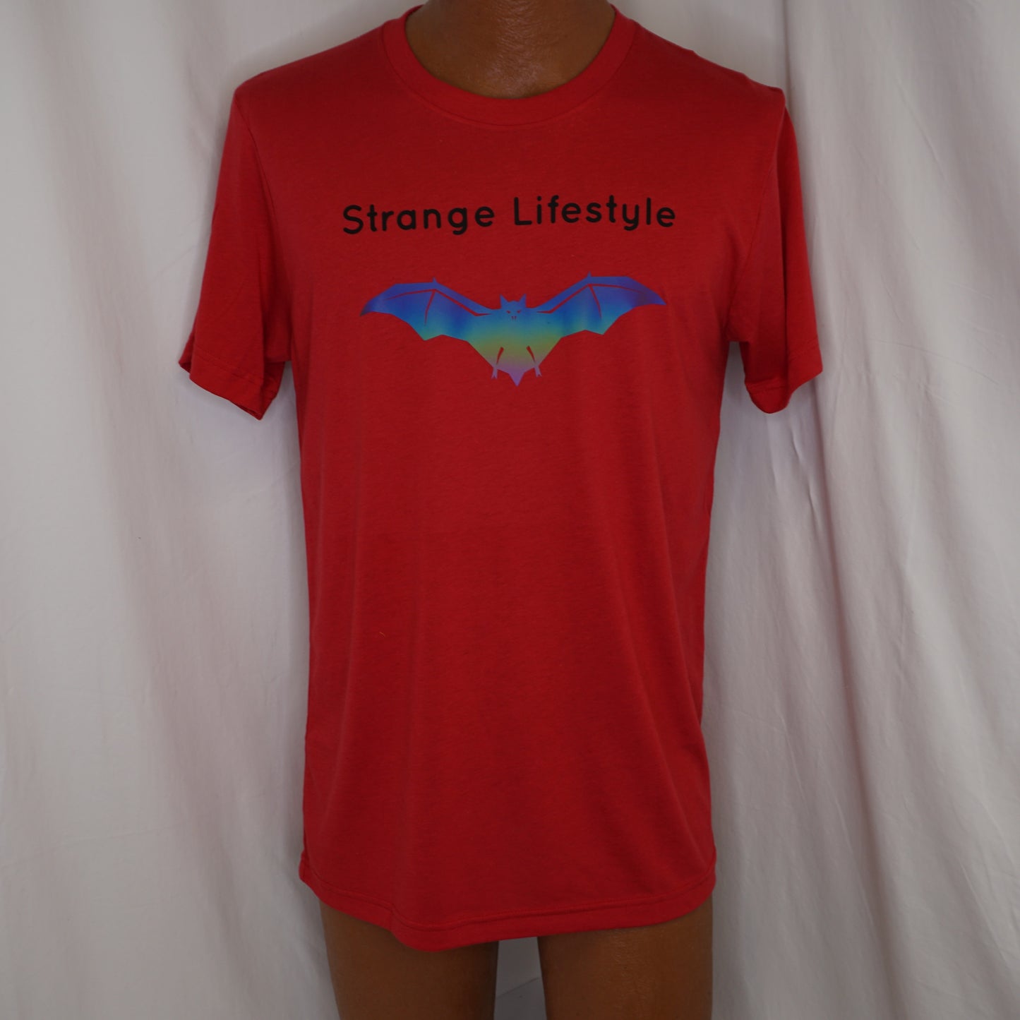 Red t-shirt with 'Strange Lifestyle' text and Strange Lifestyle bat logo graphic on a plain background